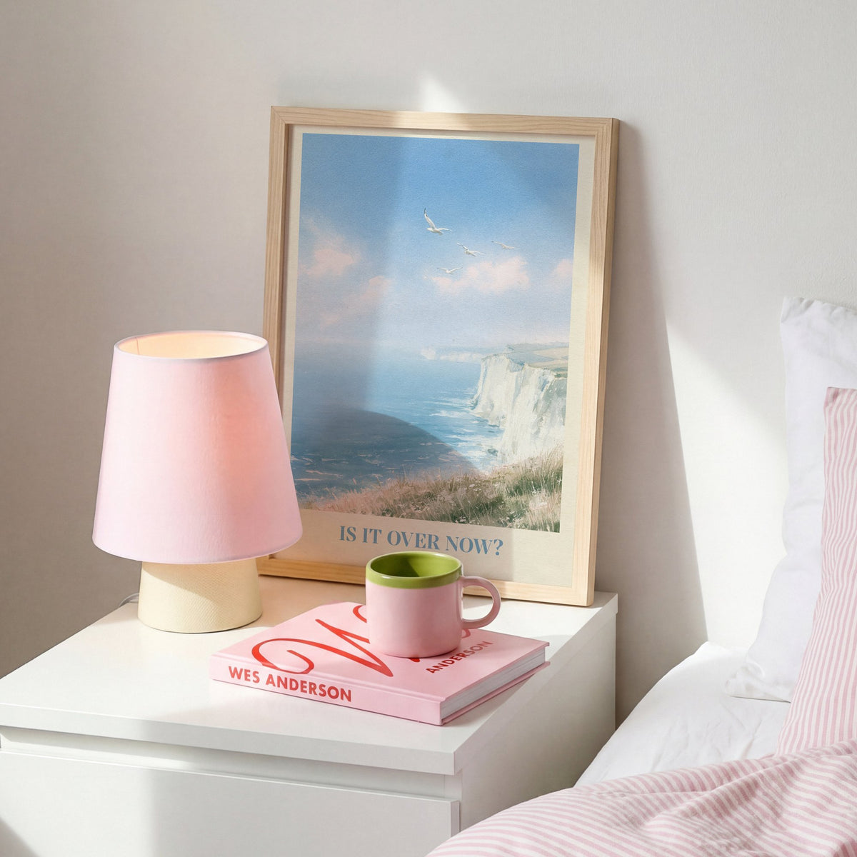 Is It Over Now? Taylor Swift print of white cliffs above a blue sea, on a white bedside table beside a pink lamp