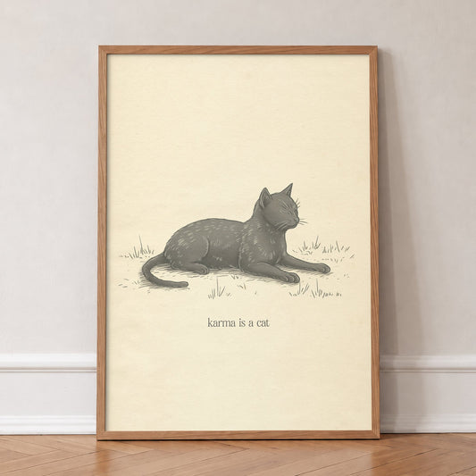 Karma Is A Cat Minimal Taylor Swift print of a sketch of a grey cat dozing in grass, in an oak frame, leaning against a wall on a herringbone floor