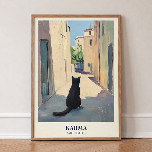 Karma Matisse Taylor Swift print of a black cat sitting in a sunny old-town street, in an oak frame, leaning against a wall on a herringbone floor