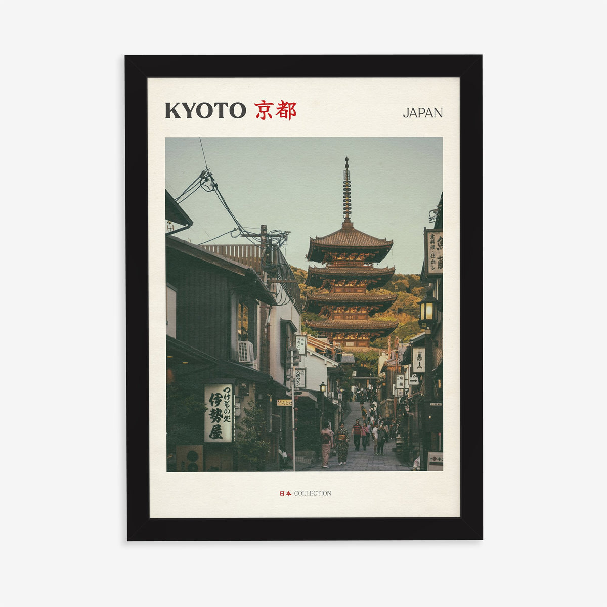 Kyoto travel print of the Yasaka Pagoda at the top of a narrow street of wooden shops, in a black frame on a plain wall