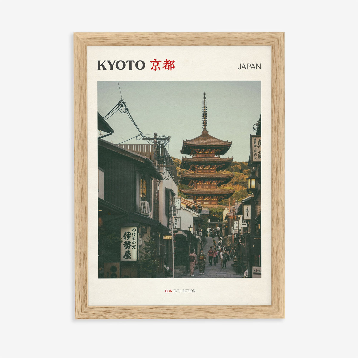 Kyoto travel print of the Yasaka Pagoda at the top of a narrow street of wooden shops, in an oak frame on a plain wall