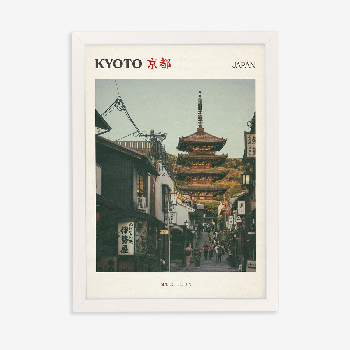 Kyoto travel print of the Yasaka Pagoda at the top of a narrow street of wooden shops, in a white frame on a plain wall