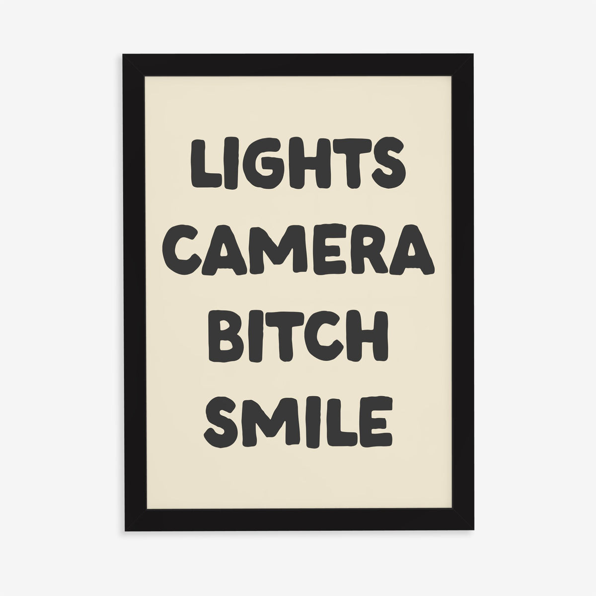 Lights Camera Bitch Smile Taylor Swift lyric print of bold black lettering on cream, in a black frame on a plain wall