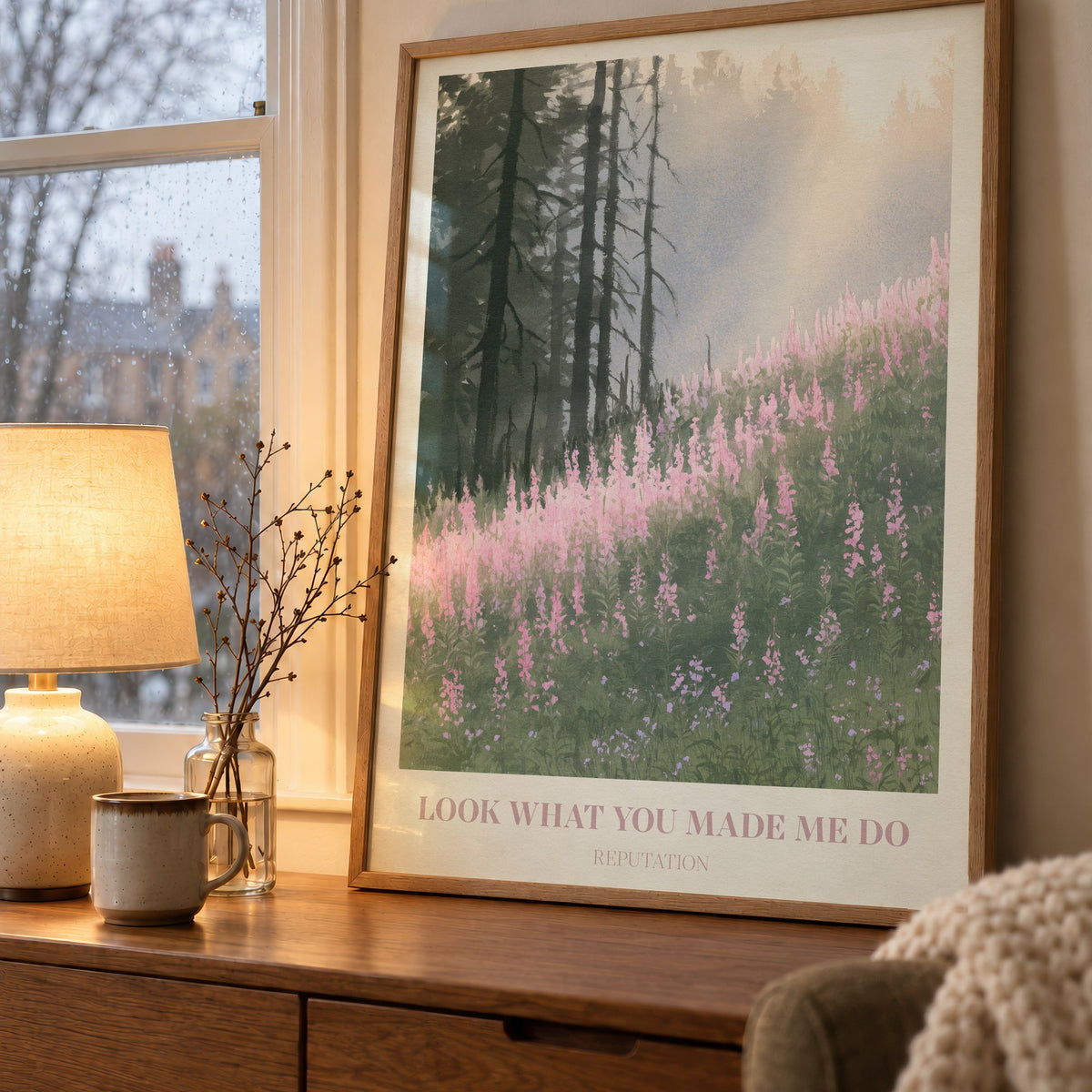 Look What You Made Me Do Taylor Swift print of pink wildflowers by pines, on a wooden sideboard by a rainy window