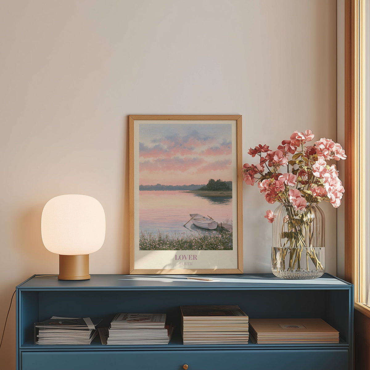 Lover Taylor Swift print of a rowing boat on a pink lake, on a blue sideboard with a lamp and flowers