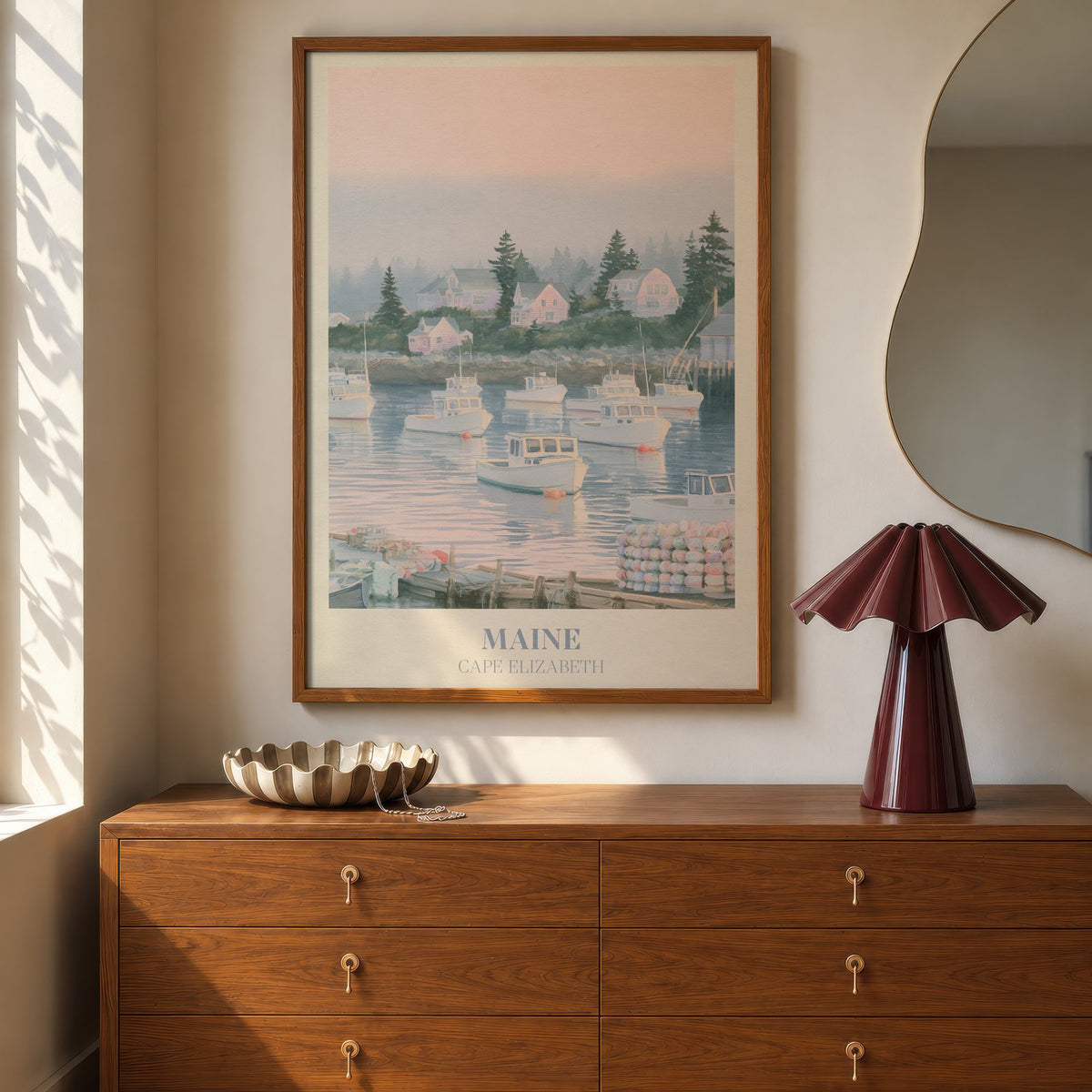 Maine Noah Kahan print of lobster boats in a misty pink harbour, hung above a walnut dresser beside a wavy mirror and a pleated lamp