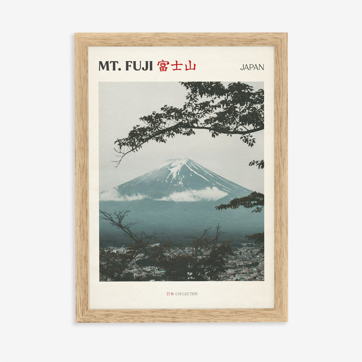 Mt Fuji travel print of snow-capped Mt Fuji framed by dark tree branches above a misty town, in an oak frame on a plain wall