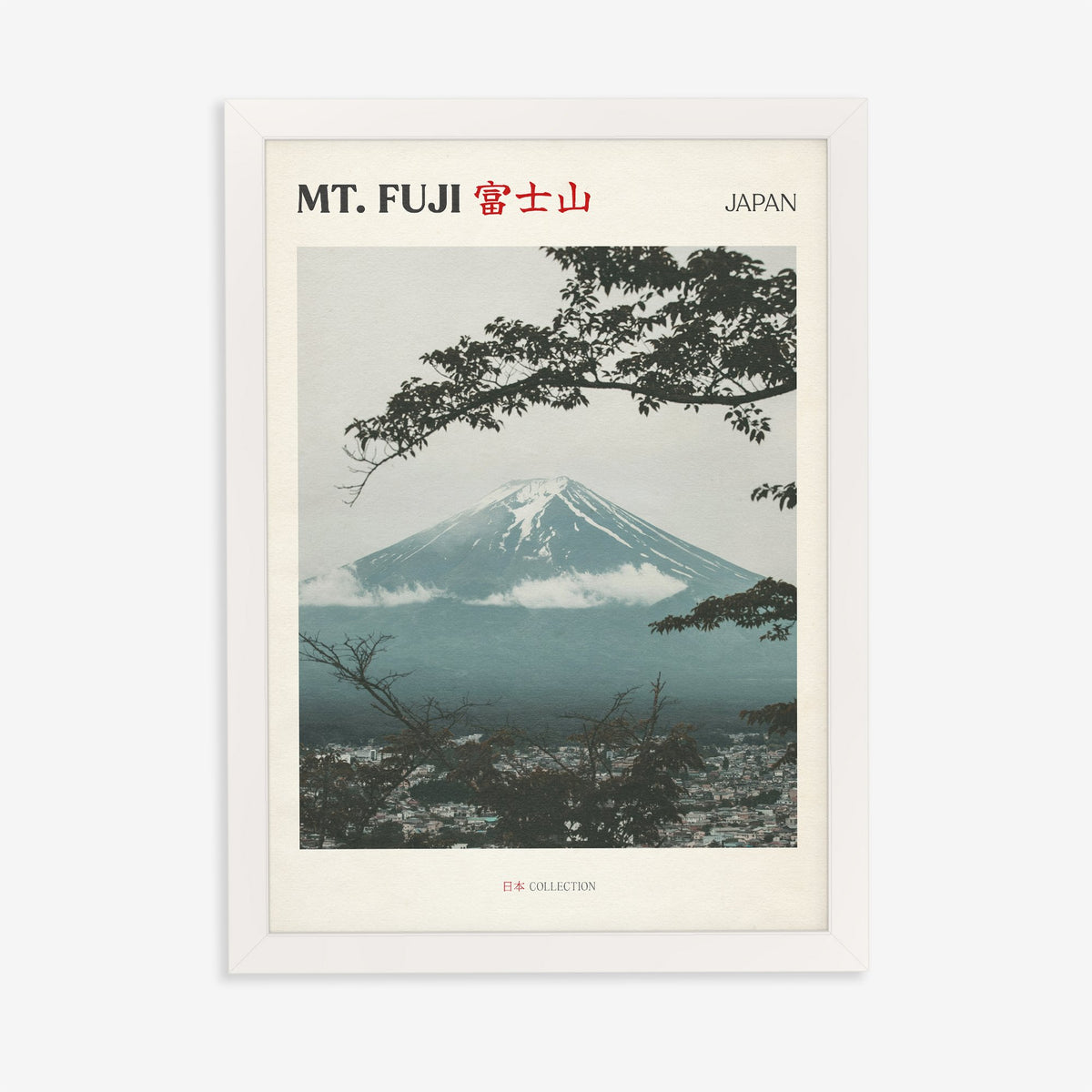 Mt Fuji travel print of snow-capped Mt Fuji framed by dark tree branches above a misty town, in a white frame on a plain wall