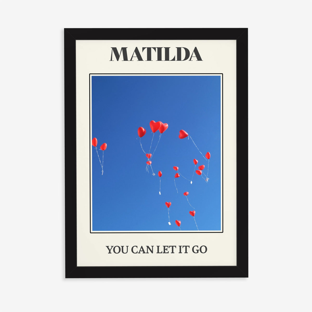Matilda Harry Styles print of red heart balloons in a deep blue sky, in a black frame on a plain wall
