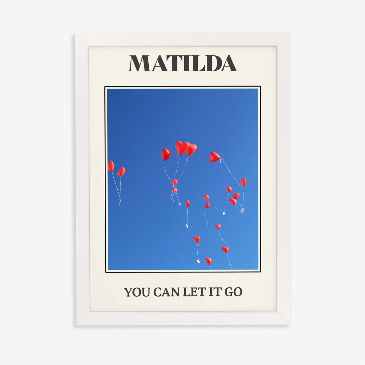 Matilda Harry Styles print of red heart balloons in a deep blue sky, in a white frame on a plain wall