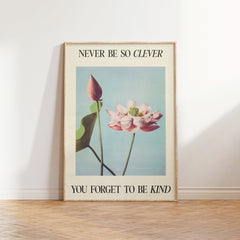 Never Be So Clever Taylor Swift print of a pink lotus on pale blue between lines of lyric, framed, leaning against a white wall