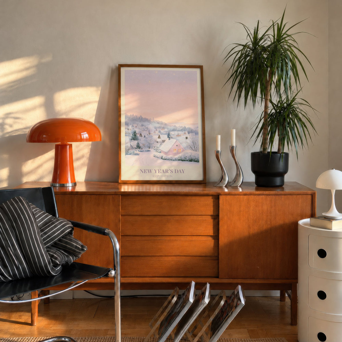 New Year’s Day Taylor Swift print of a snowy pink cottage, leaning on a mid-century sideboard beside an orange lamp