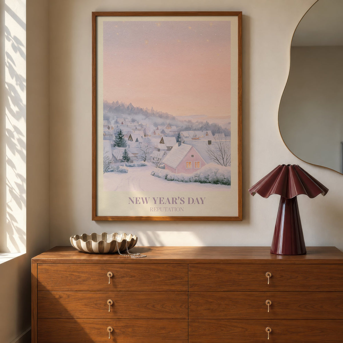 New Year’s Day Taylor Swift print of a snowy pink cottage, hung above a walnut dresser beside a wavy mirror and a pleated lamp