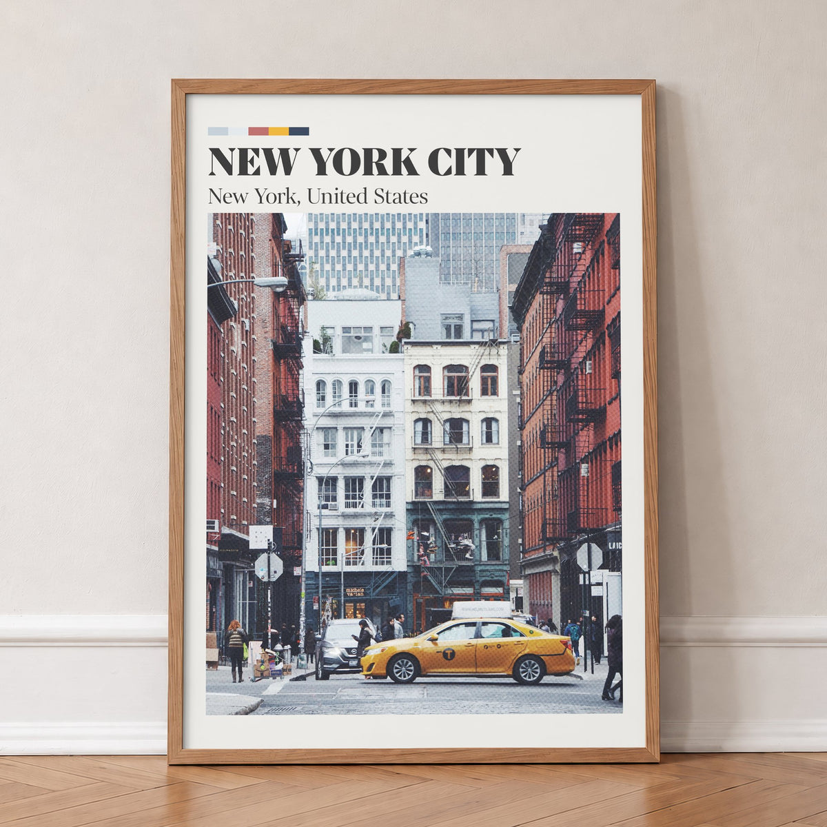 New York City travel print of an old brick street with fire escapes and a yellow taxi, in an oak frame, leaning against a wall on a herringbone floor