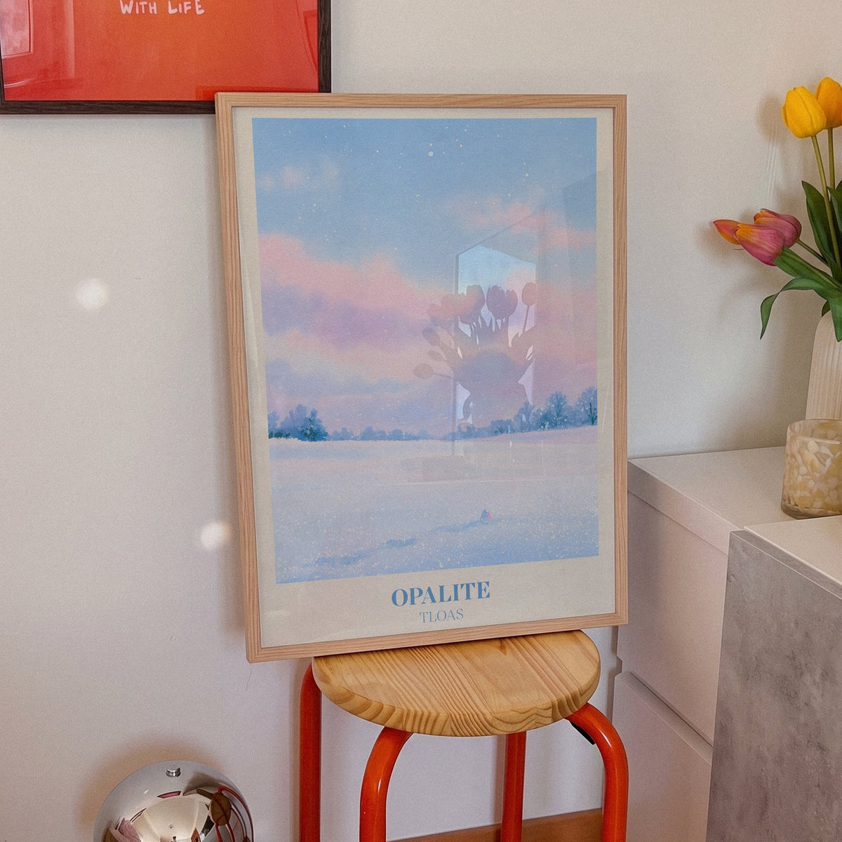 Opalite Winter Taylor Swift print of pink clouds over a snowy field, on an orange stool beside tulips