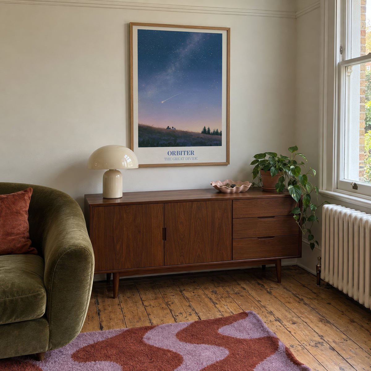 Orbiter Noah Kahan print of two people watching a shooting star from a hillside, hung above a mid-century sideboard