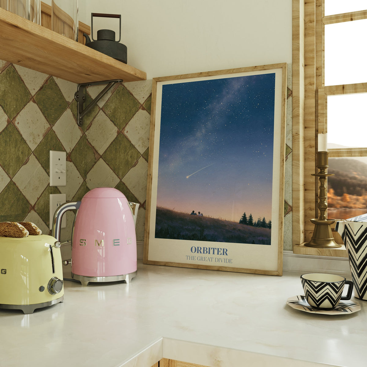 Orbiter Noah Kahan print of two people watching a shooting star from a hillside, on a kitchen counter beside a kettle and toaster