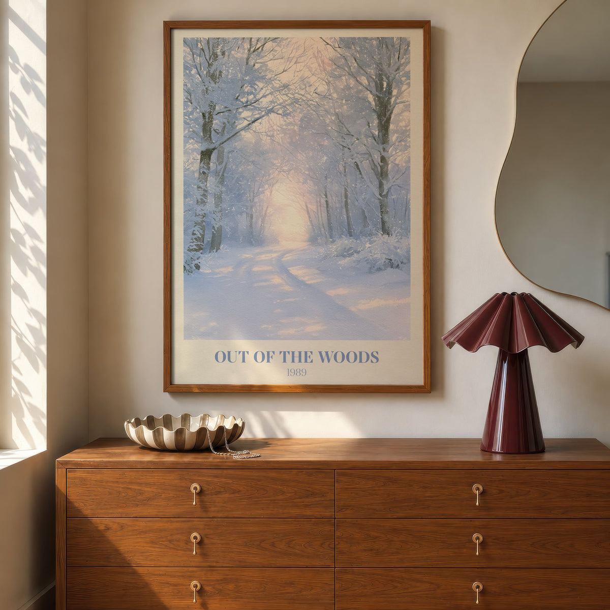 Out Of The Woods Winter Taylor Swift print of a snowy woodland path, hung above a walnut dresser beside a wavy mirror and a pleated lamp