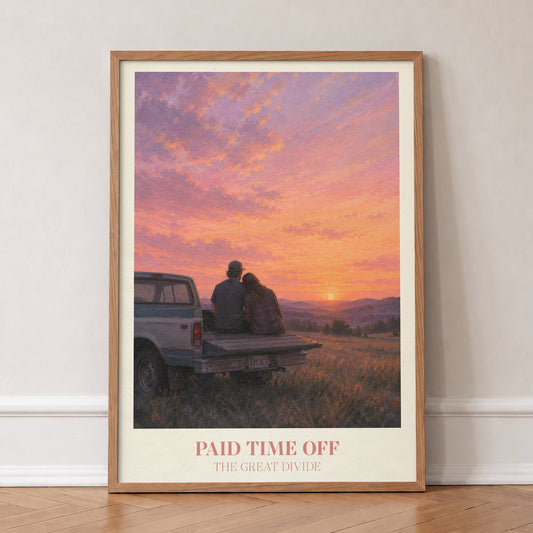 Paid Time Off Noah Kahan print of a couple on a truck watching a pink sunset, in an oak frame, leaning against a wall on a herringbone floor