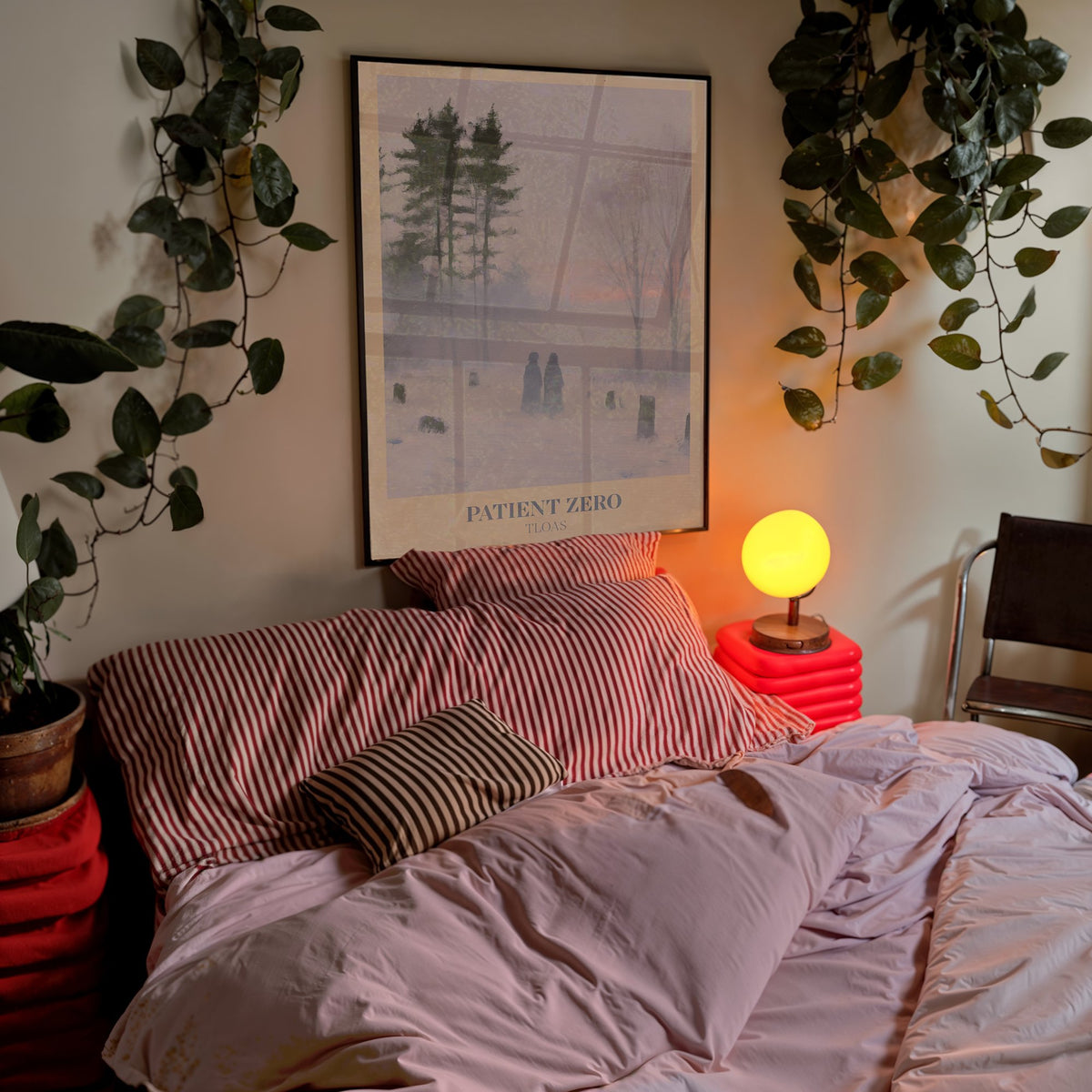 Patient Zero Taylor Swift print of two figures in a snowy mist, hung above a bed with trailing plants and a glowing orb lamp