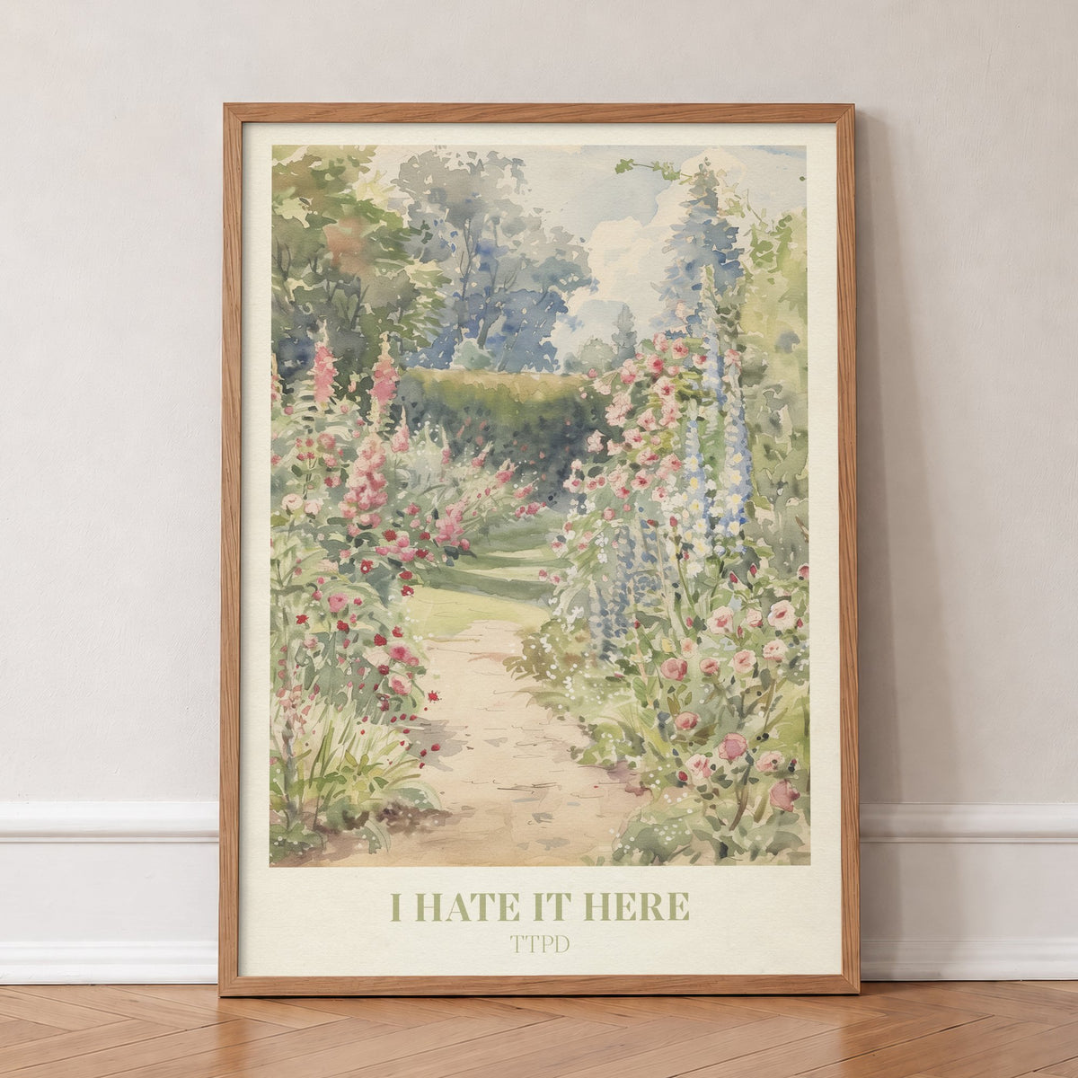 I Hate It Here Taylor Swift print of a garden path lined with foxgloves and roses, in an oak frame, leaning against a wall on a herringbone floor