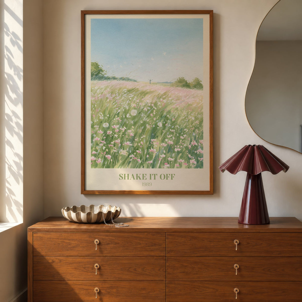 Shake It Off Taylor Swift print of a pink wildflower meadow, hung above a walnut dresser beside a wavy mirror and a pleated lamp