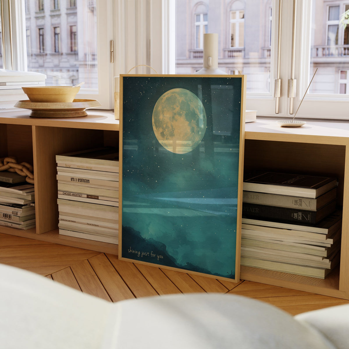Shining Just For You Taylor Swift print of a full moon over a starry blue night sky, framed on a bookcase by a window