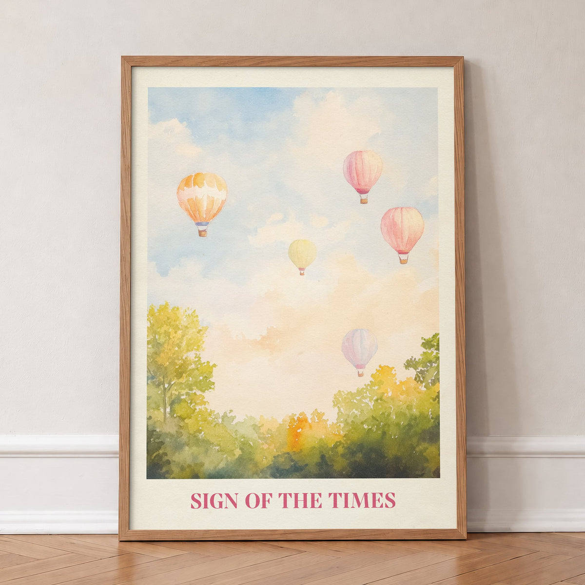 Sign Of The Times Harry Styles print of hot air balloons over trees in a pastel sky, in an oak frame, leaning against a wall on a herringbone floor
