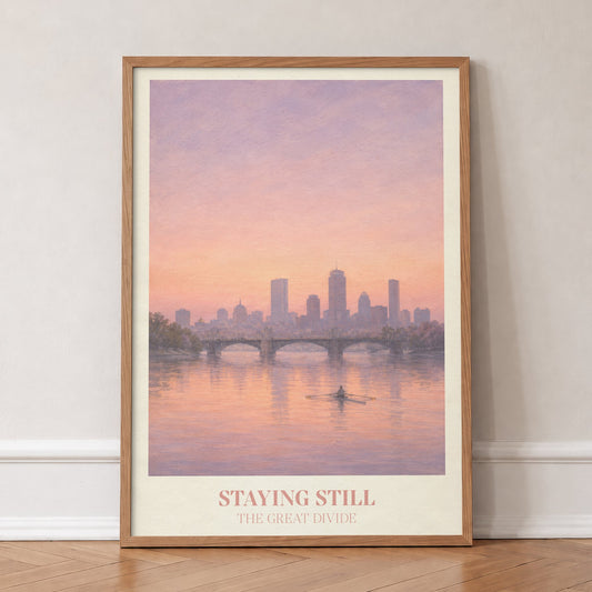 Staying Still Noah Kahan print of a lone rower on a pink river below a city skyline, in an oak frame, leaning against a wall on a herringbone floor