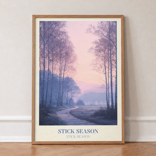 Stick Season Noah Kahan print of a misty path through bare birch trees under a pink sky, in an oak frame, leaning against a wall on a herringbone floor