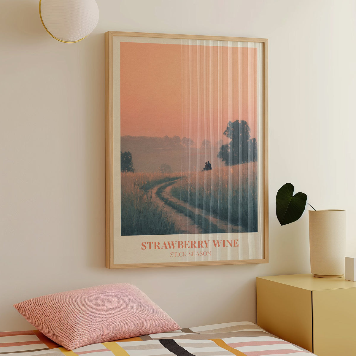 Strawberry Wine Noah Kahan print of two figures in a golden meadow under a peach sky, framed above a bed