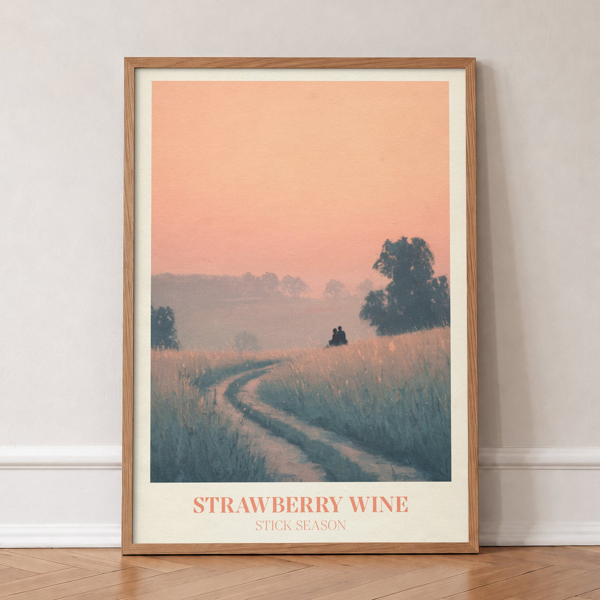 Strawberry Wine Noah Kahan print of two figures in a golden meadow under a peach sky, in an oak frame, leaning against a wall on a herringbone floor