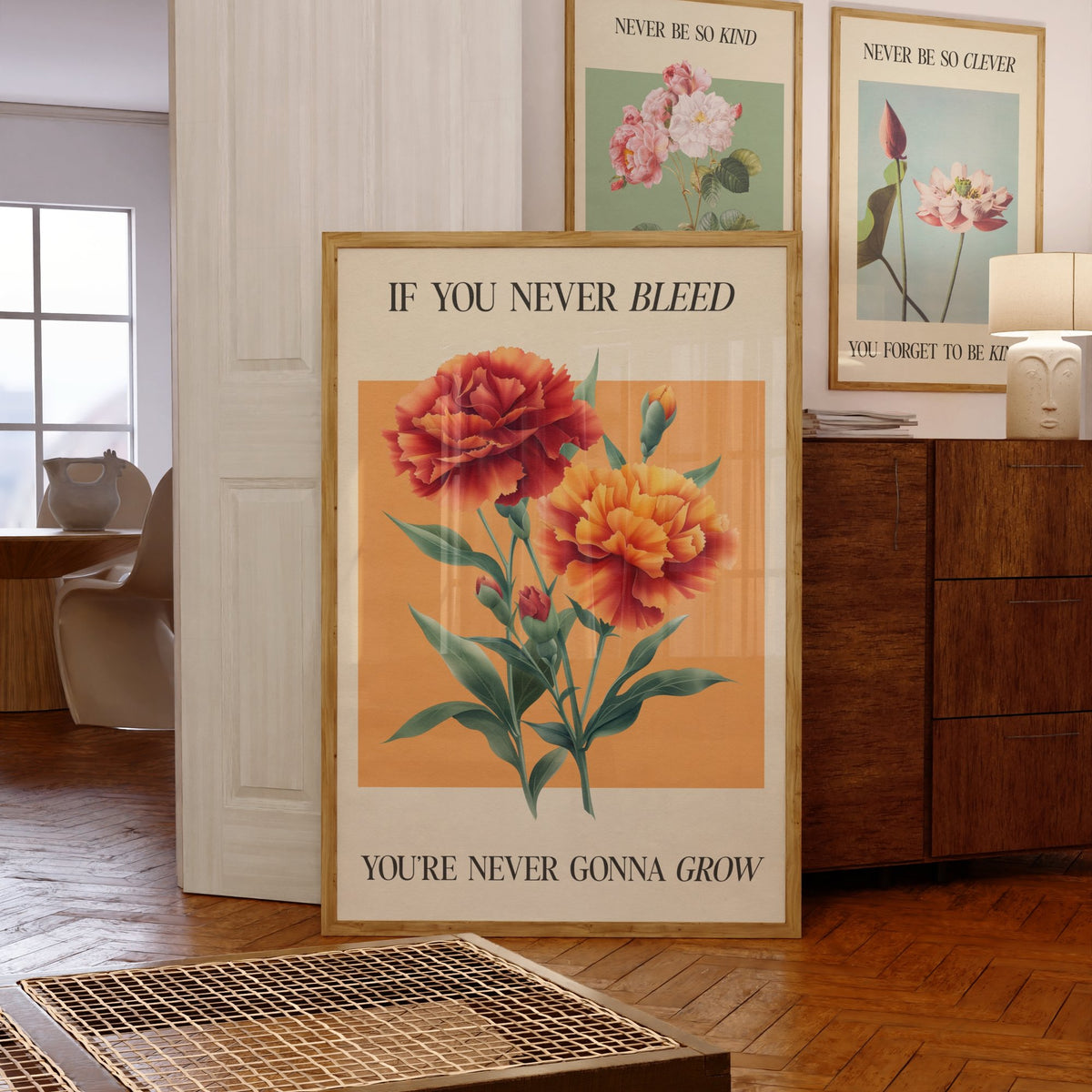 The 1 Botanical Taylor Swift print of red and orange carnations on a peach square, framed, leaning against a chest of drawers