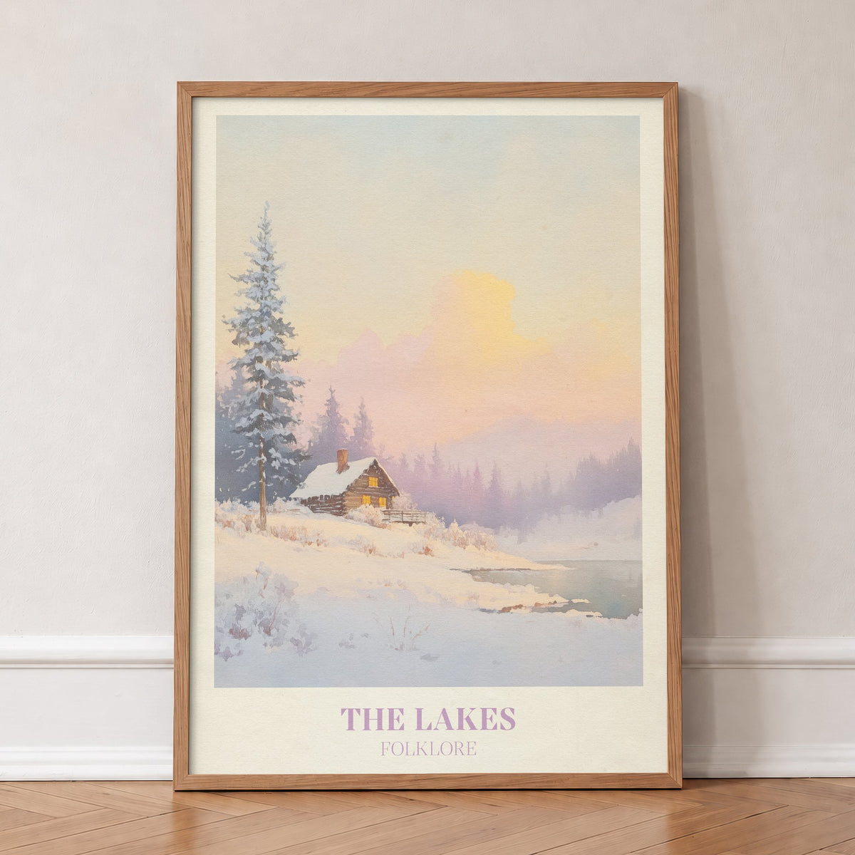The Lakes Christmas Taylor Swift print of a snowy log cabin by a lake under a pink sky, in an oak frame, leaning against a wall on a herringbone floor
