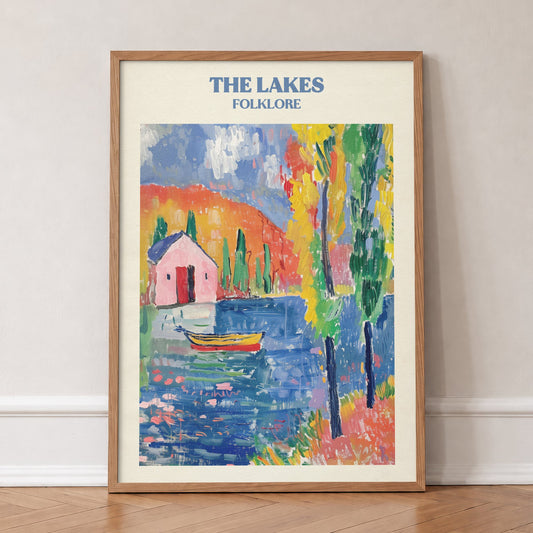 The Lakes Matisse Taylor Swift print of a pink cottage and a boat on a bright blue lake, in an oak frame, leaning against a wall on a herringbone floor