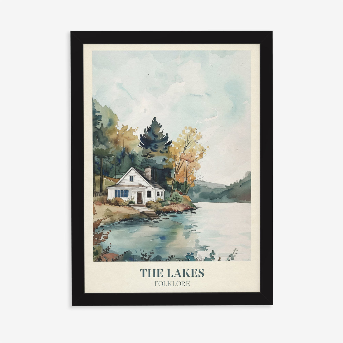 The Lakes Taylor Swift print of a white cottage beside a still lake and trees, in a black frame on a plain wall