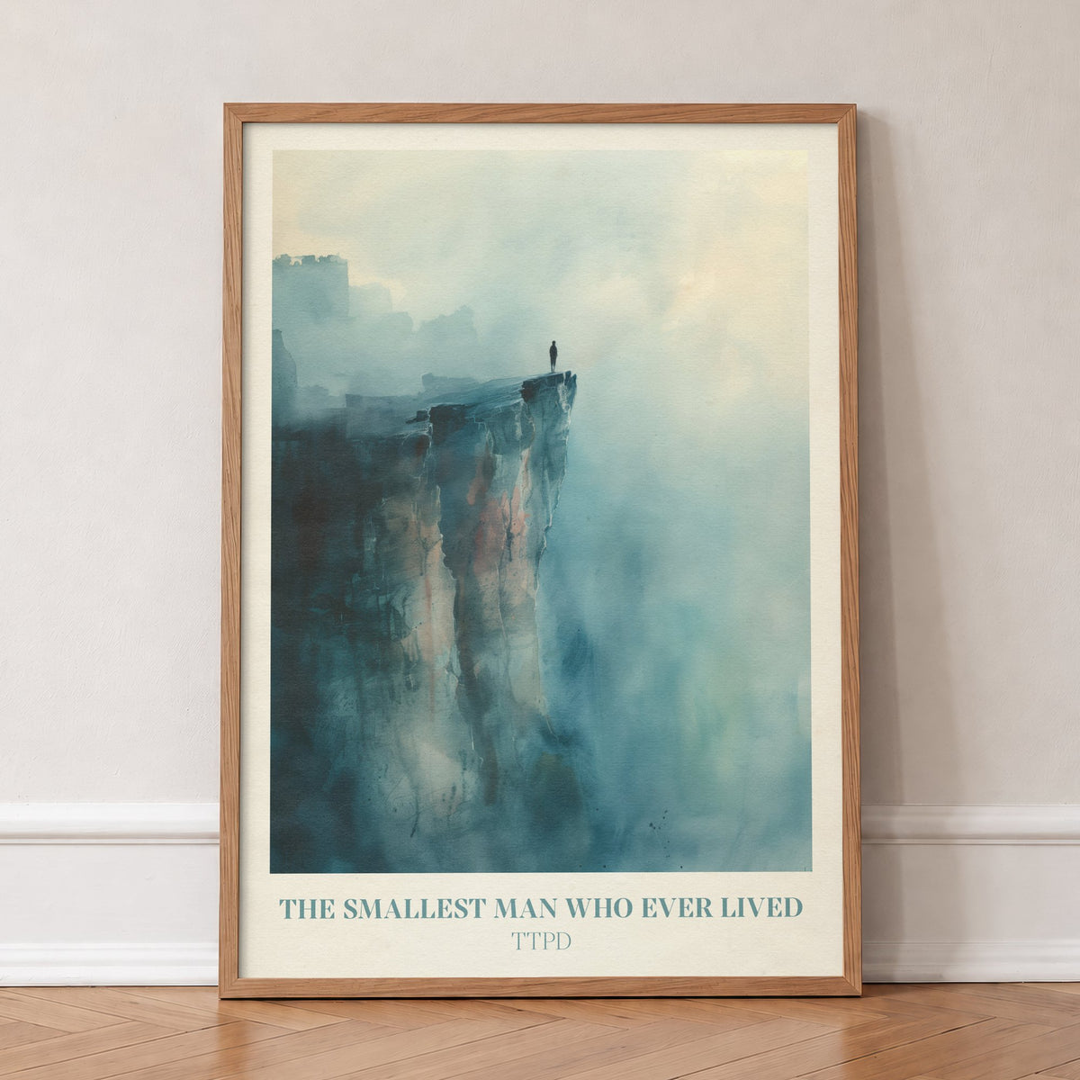 The Smallest Man Who Ever Lived Taylor Swift print of a lone figure on a misty blue cliff, in an oak frame, leaning against a wall on a herringbone floor