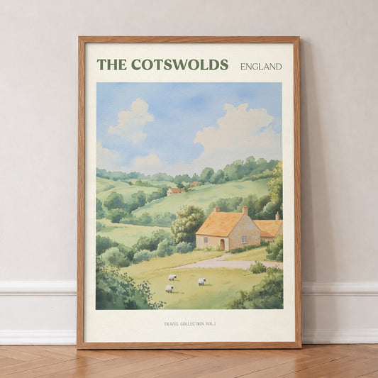 Cotswolds travel print of a honey-coloured stone cottage in rolling green hills with sheep, in an oak frame, leaning against a wall on a herringbone floor