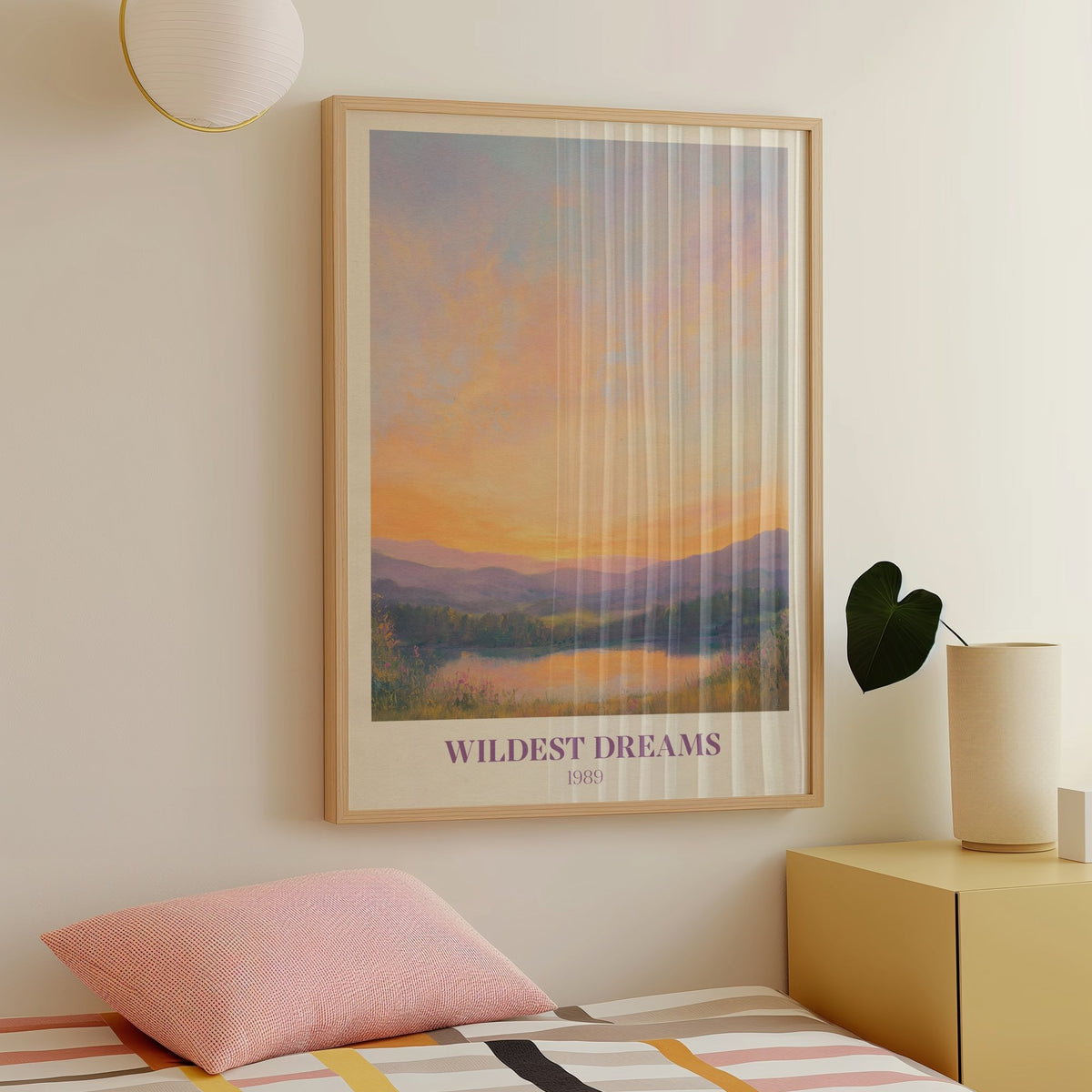 Wildest Dreams Taylor Swift print of a painted peach and lilac sunset over hills and a lake, framed above a bed