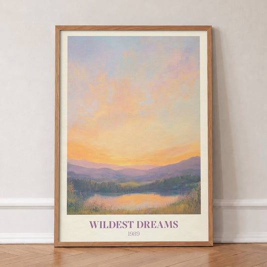 Wildest Dreams Taylor Swift print of a painted peach and lilac sunset over hills and a lake, in an oak frame, leaning against a wall on a herringbone floor