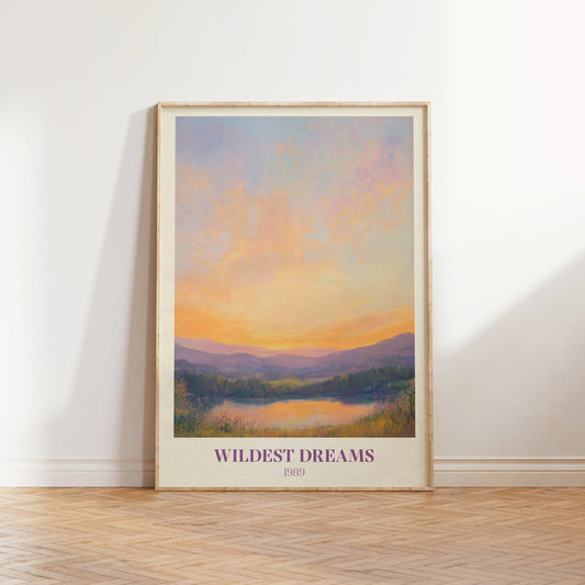 Wildest Dreams Taylor Swift print of a painted peach and lilac sunset over hills and a lake, framed, leaning against a white wall