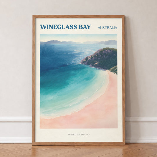 Wineglass Bay travel print of a curved white beach and turquoise water in Tasmania, in an oak frame, leaning against a wall on a herringbone floor