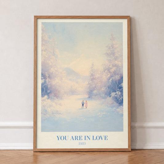 You Are In Love Taylor Swift print of a couple holding hands on a snowy path, in an oak frame, leaning against a wall on a herringbone floor