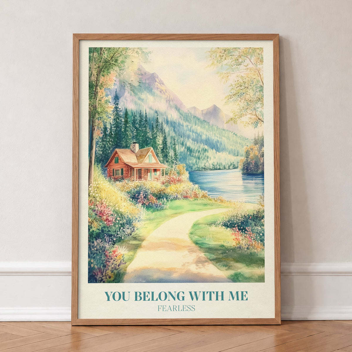 You Belong With Me Taylor Swift print of a red cabin by a mountain lake with a flowery path, in an oak frame, leaning against a wall on a herringbone floor
