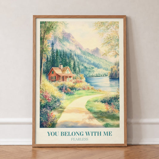 You Belong With Me Taylor Swift print of a red cabin by a mountain lake with a flowery path, in an oak frame, leaning against a wall on a herringbone floor